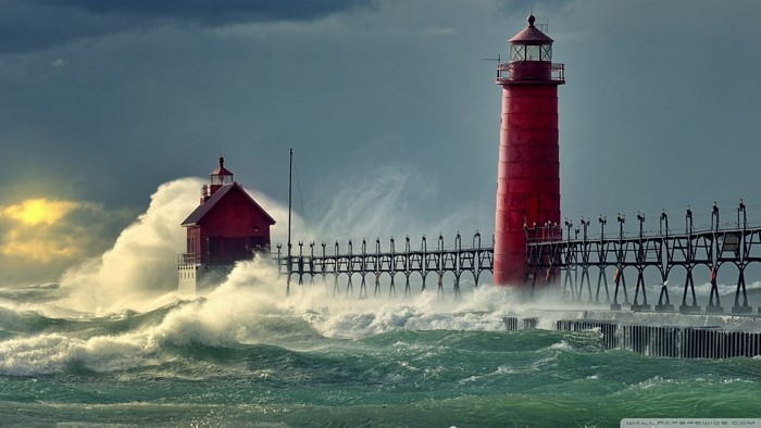 Red lighthouses on a pier during a storm with large waves