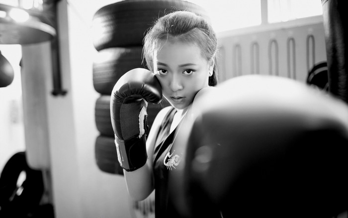 Young Asian woman in boxing gloves in a gym