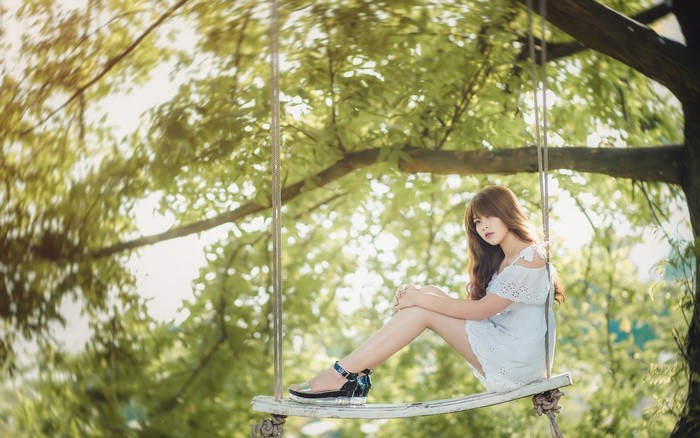 Woman sitting on a swing under a tree