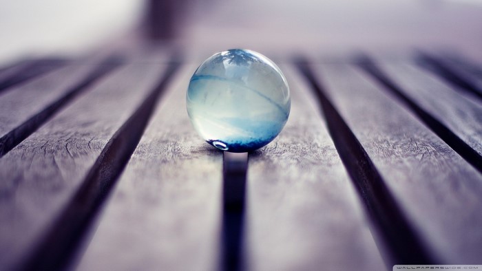 Glass marble with blue swirls on wooden surface