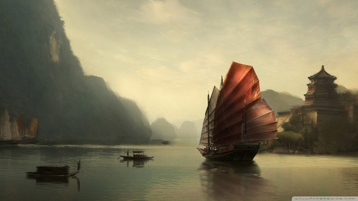 Junk boat sailing in a misty bay with mountains and a pagoda