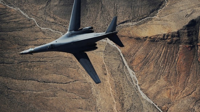 Rockwell B-1 Lancer bomber flying over desert terrain