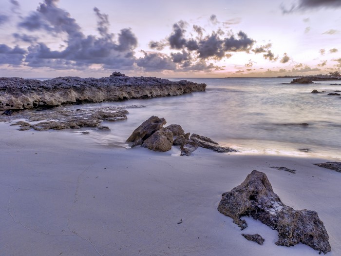 Rocky shore at sunset with clouds over the ocean