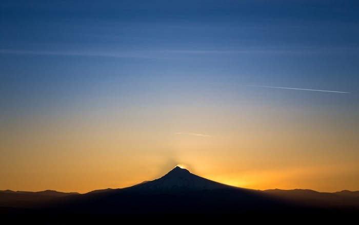 Sunset over mountains with contrail