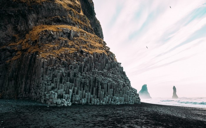 Basalt columns on a black sand beach with sea stacks