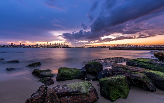 Sydney skyline at sunset with harbor bridge and rocks