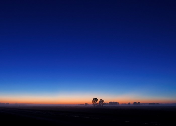 Dark blue sky over a misty plain at dawn