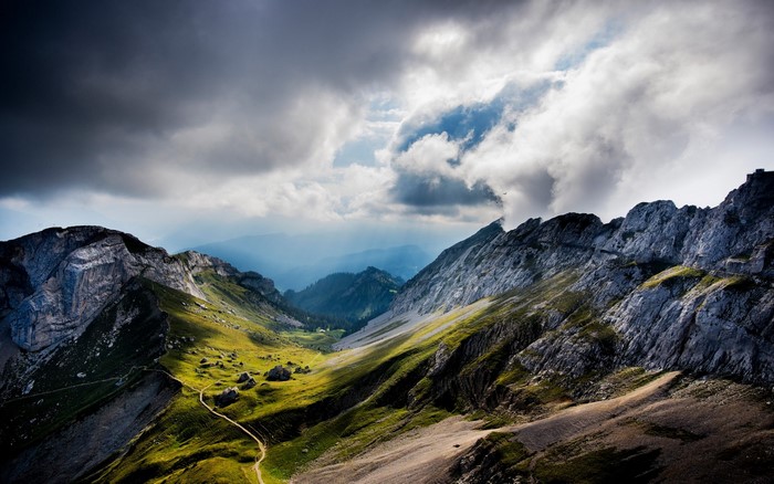 Dramatic mountain landscape with stormy clouds and sunlit valley