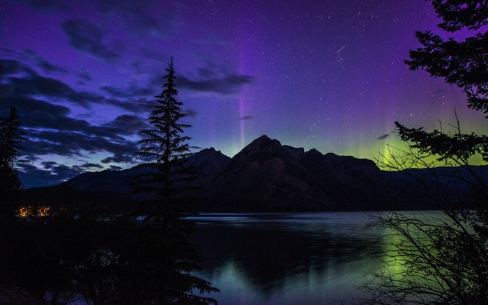 Aurora Borealis over mountains and lake at night