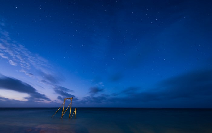 Wooden structure in the sea under a starry night sky