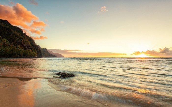 Sunset over the ocean with mountains and beach