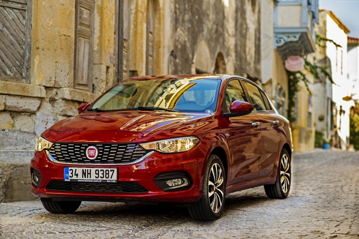 Red Fiat Egea parked on a cobblestone street