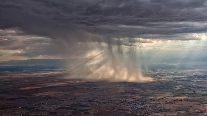 Sunlight beams through rain clouds over a landscape
