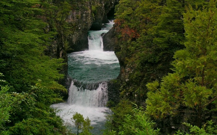 Waterfalls flowing through a lush green canyon in Chile