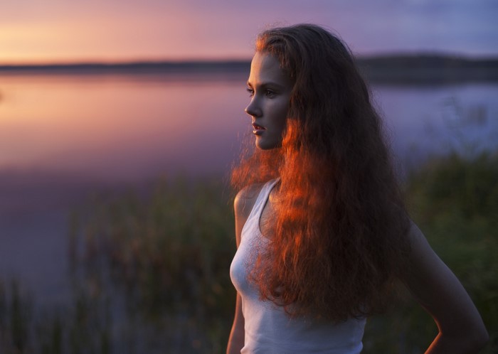 Woman with wavy hair at sunset by the water