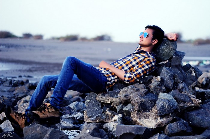 Man in plaid shirt and sunglasses relaxing on rocks