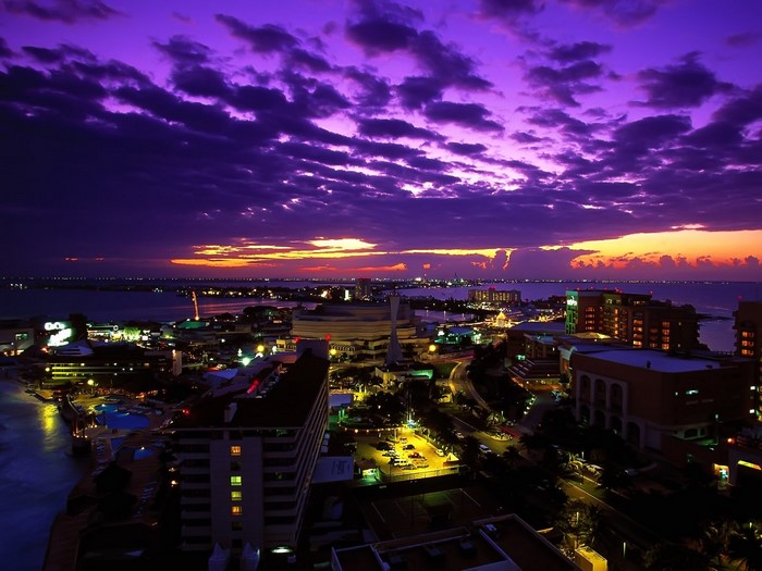 Cityscape at dusk with purple clouds over the ocean