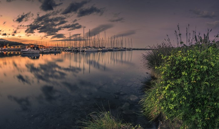 Boats in a harbor at sunset with reflections
