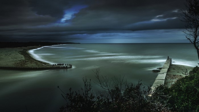 Long exposure of a pier and coastline at night