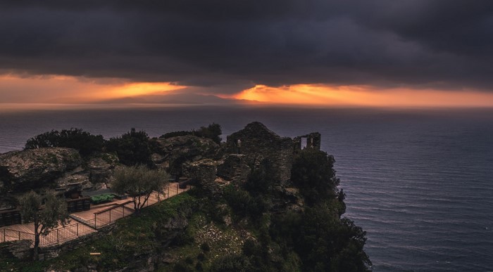 Ruins on a cliff overlooking the sea at sunset