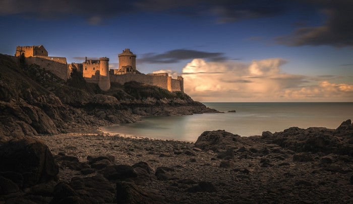 Castle on a rocky cliff overlooking the sea at sunset