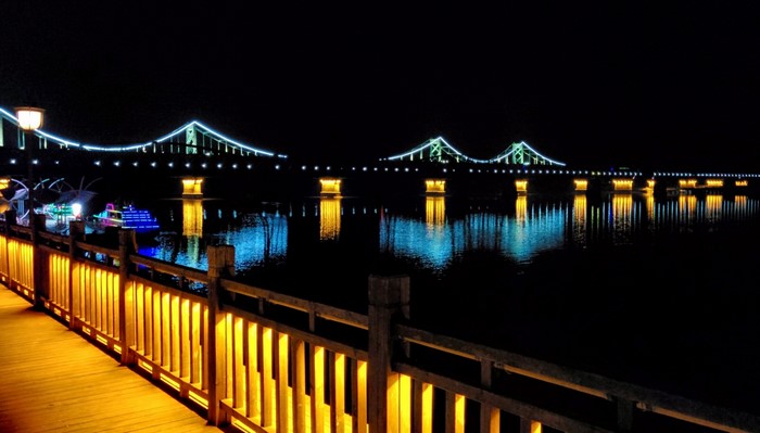 Bridge illuminated at night with reflections on water