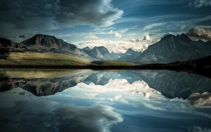Mountain range reflected in a calm lake under a cloudy sky