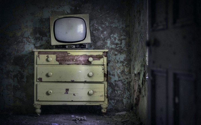 Old television on a dresser in a dark room