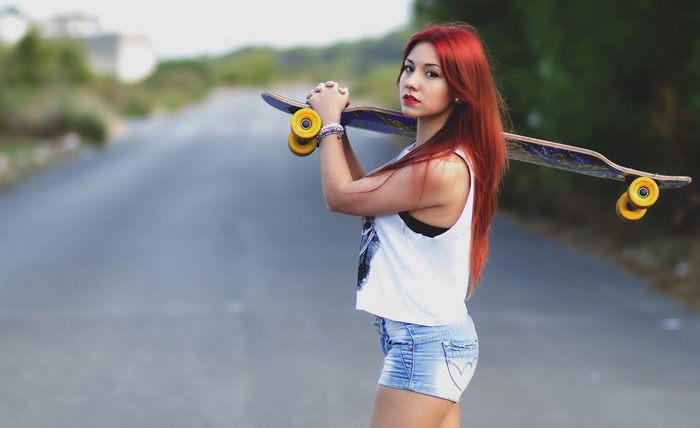 Redhead woman with skateboard on a road
