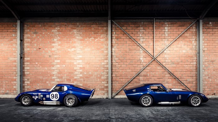 Two blue Shelby Cobra Daytona race cars in a brick building