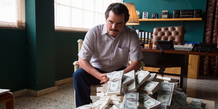 Pablo Escobar from Narcos sitting with money