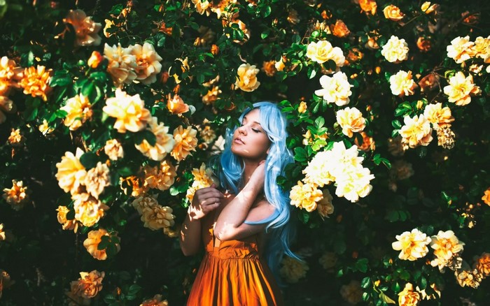 Woman with blue dyed hair in a field of yellow flowers