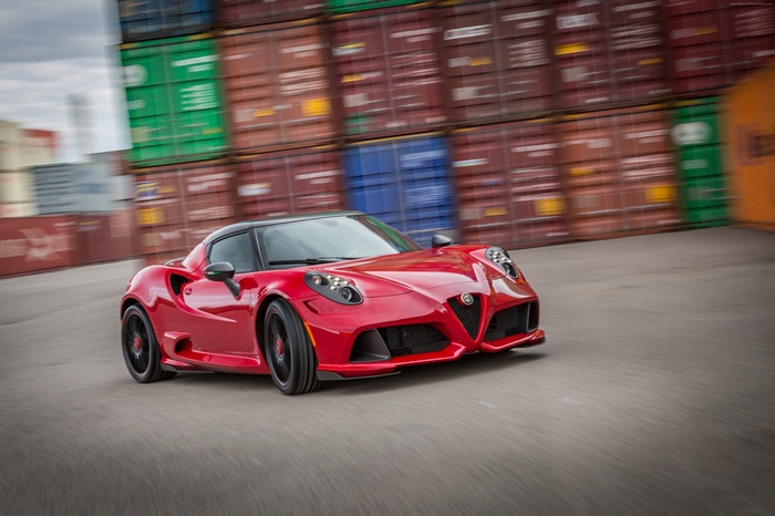 Red Alfa Romeo 4C sports car driving past shipping containers