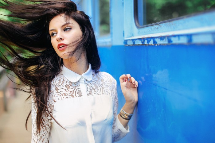 Woman with long dark hair leaning against a blue train