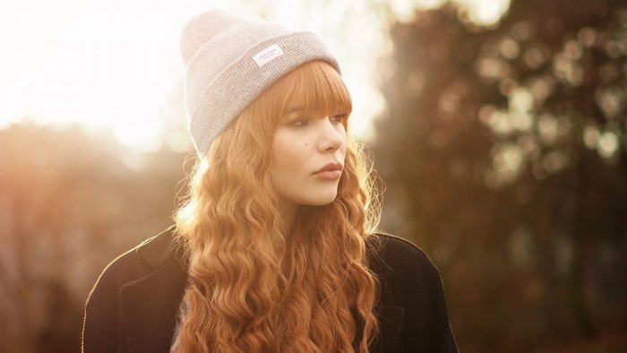 Woman with red hair wearing a beanie and coat