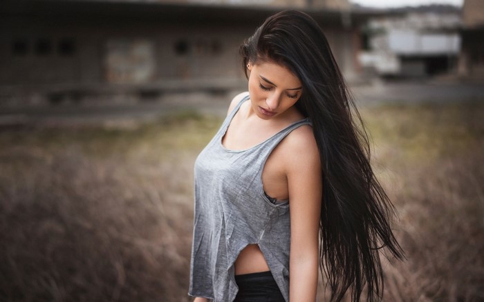 Woman with long black hair in a tank top outdoors
