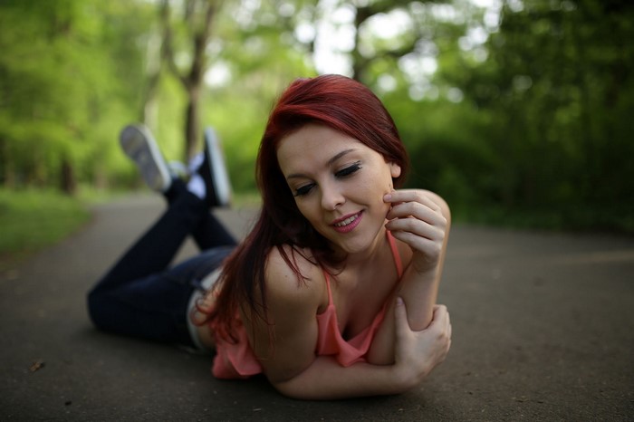 Redhead woman lying on a path in a park