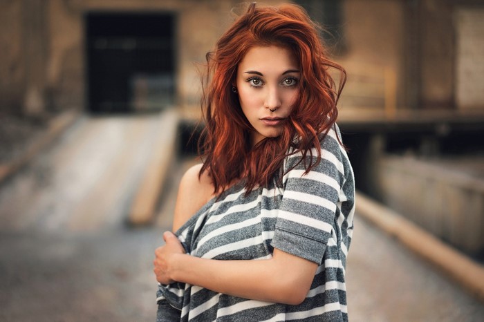 Woman with red hair and nose ring wearing striped shirt