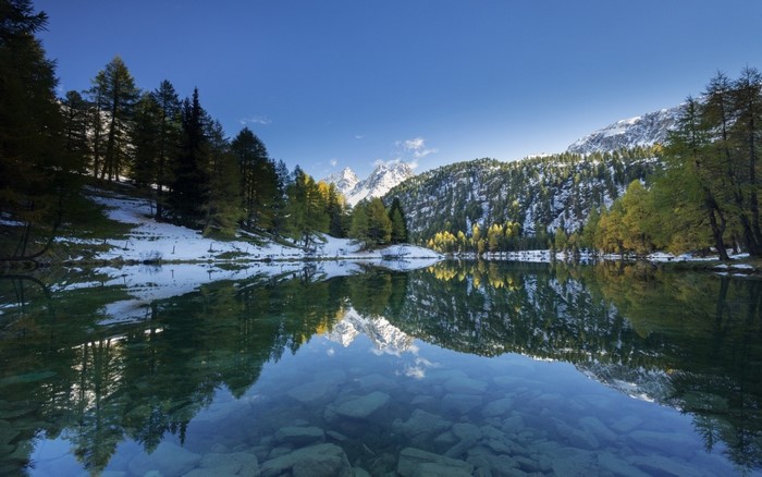 Lake reflection of snow-capped mountains and autumn trees