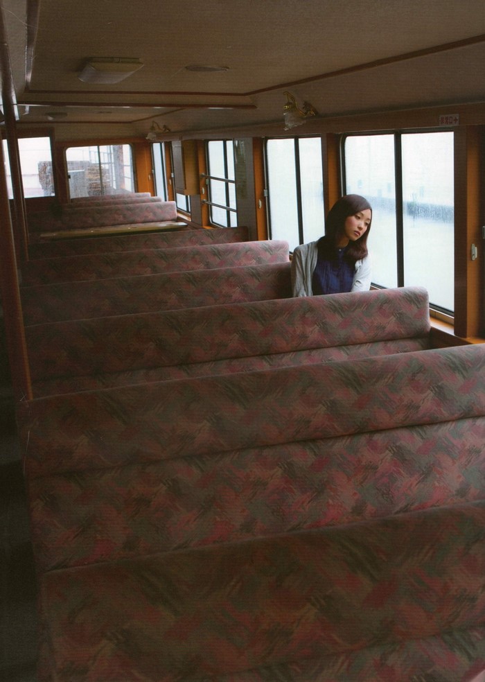 Woman sitting on a boat interior with rows of seats