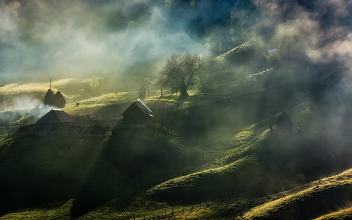 Misty morning over a rural village with haystacks