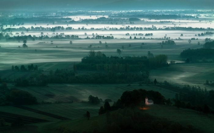 Misty valley with a small church at dawn