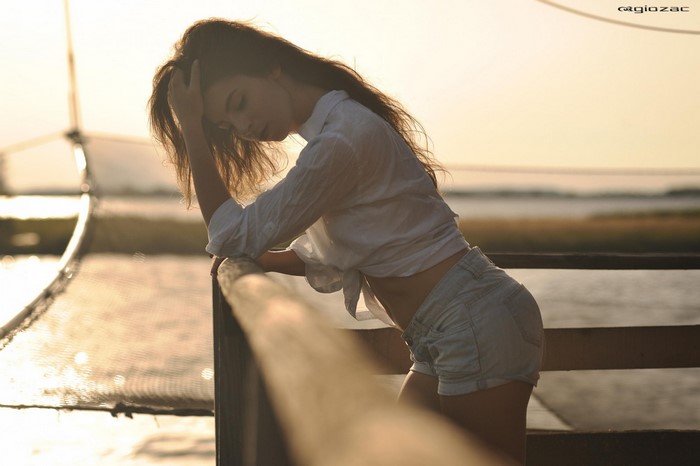 Woman in white shirt and jean shorts leaning on railing