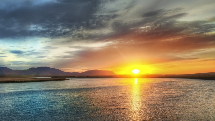 Sunset over a river with mountains in the distance
