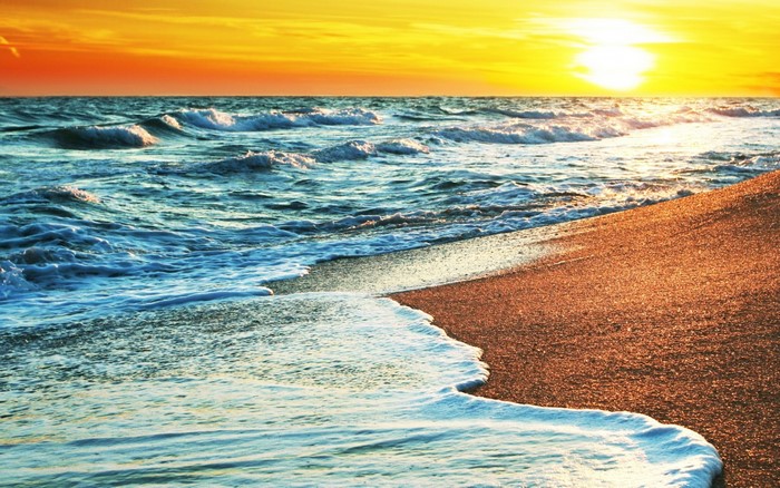 Sunset over the ocean waves crashing on the shore