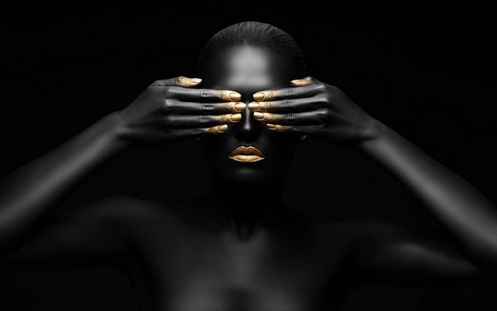 Woman with black skin and gold accents covering eyes