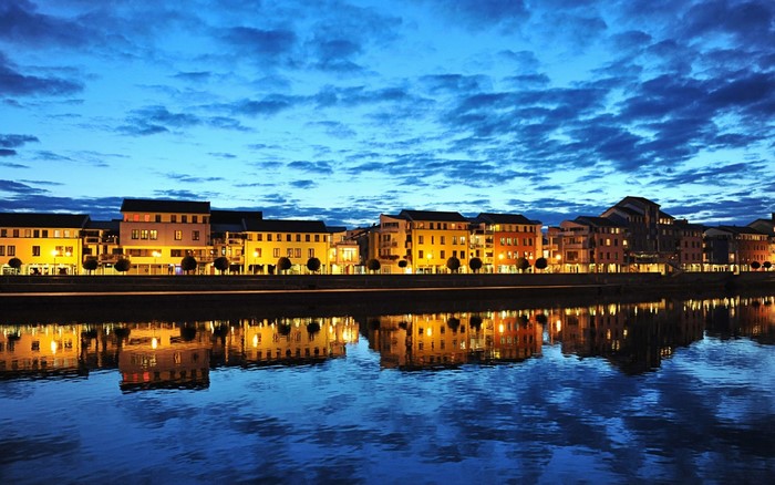 Cityscape with buildings and river reflection at dusk