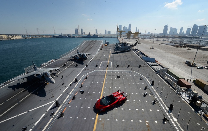 Red supercar on an aircraft carrier with jets and helicopters