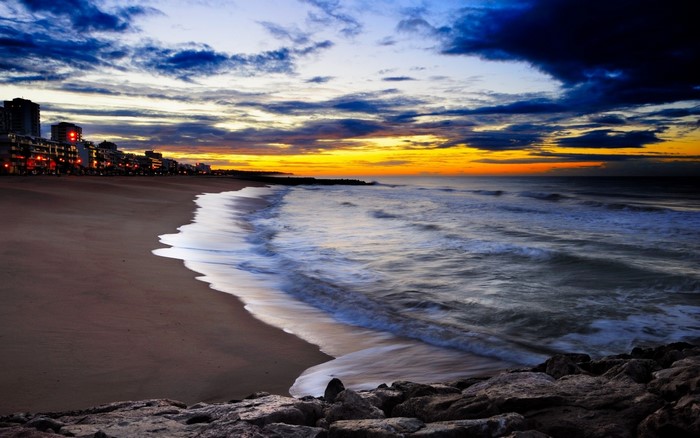 Beach cityscape at sunset with ocean waves