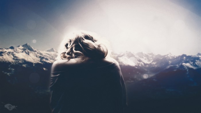 Woman with blonde hair in front of snowy mountains